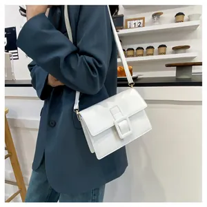 Chic white leather crossbody bag with iconic square buckle shown on casual blazer