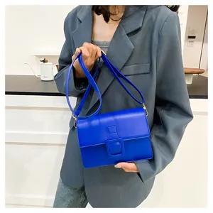 Detail shot of a bright blue crossbody bag with a large buckle and matte texture