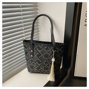 Black canvas tote bag with beige geometric floral patterns and white tassel charm