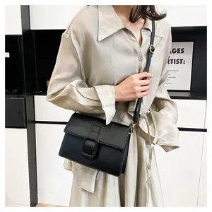 Detail of minimalist black square crossbody bag with square buckle on a female model