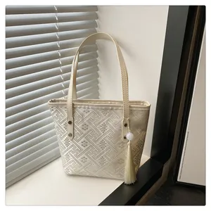 Chic beige embroidered tote bag with tassel charm for elegant summer commuting fashion