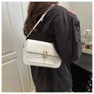 Gros plan du sac bandoulière blanc en cuir avec un fermoir doré en fer à cheval sur un modèle