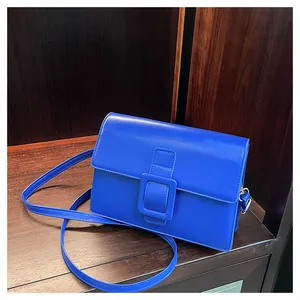 Close-up of vibrant blue rectangular crossbody bag with signature large square buckle