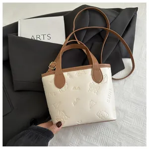 Close-up of embossed puppy and butterfly patterns on a cream and brown bucket bag