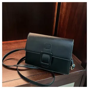 Detail of black leather square bag showing the large buckle and smooth texture finish