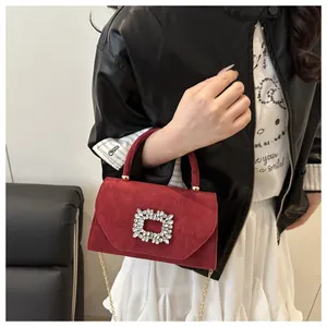 Detail of burgundy suede handbag featuring a signature crystal square buckle and chain strap
