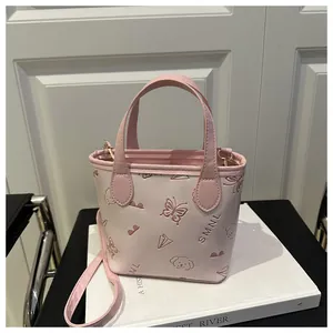 Detailed view of pink bucket bag featuring embossed butterflies and logo with detachable strap