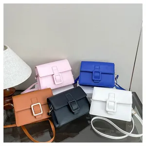Detail of colorful crossbody bags with large square buckles on a glass surface