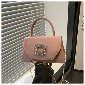 Close-up of pink suede handbag with a luxury crystal buckle and gold chain strap