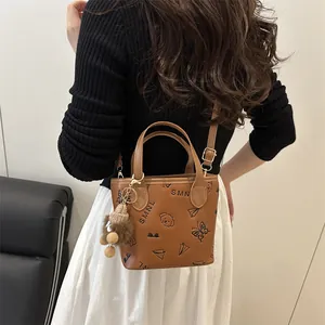 Brown leather bucket bag with embossed patterns and bear charm worn by a model