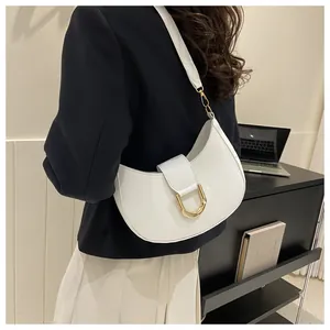 Close-up of a white crescent shoulder bag with golden D-ring buckle worn by a model