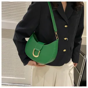 Detail view of stylish green crescent shoulder bag with large gold buckle on model