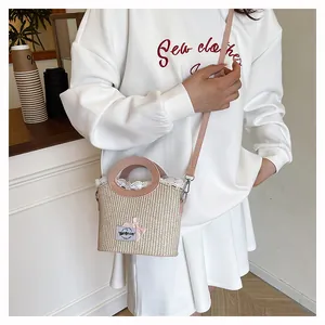 Detail of beige woven straw bag with pink leather handles and lace trim edge
