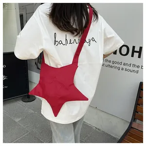 Detail shot of a red star-shaped crossbody bag worn over a white casual t-shirt