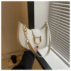 Detail of white crescent shoulder bag with large gold U-buckle and metal chain strap