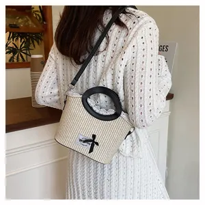 Detail of beige woven basket bag with lace trim, black bow, and adjustable leather strap