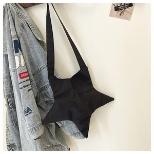 Detail of black star-shaped crossbody bag made of nylon hanging with denim jacket