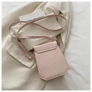 Detail of light pink PU leather mini crossbody bag with gold hardware on white blazer