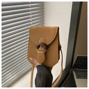 Detailed view of camel faux suede mini crossbody bag with a large wood grain buckle
