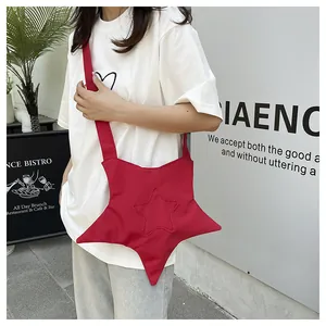 Détail d'un sac à bandoulière rouge vif en forme d'étoile porté par un mannequin de rue chic