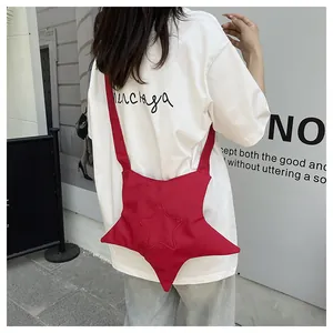 Photo en extérieur d'un sac bandoulière rouge vif en forme d'étoile avec sangle large