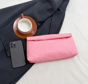 Pink woven envelope clutch detail with fold-over design and gold metal fastener