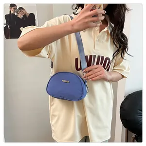 Dettaglio della borsa a conchiglia in nylon viola con logo dorato e tracolla larga