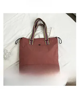 Close-up of retro reddish-brown tote bag with colorful striped handles on white fabric