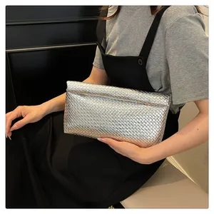 Close-up of silver woven leather clutch featuring detailed metallic texture and fold design