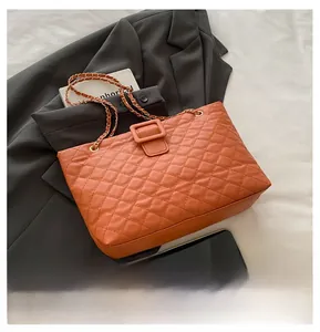 Close-up of caramel quilted leather tote bag with elegant chain strap and metal buckle