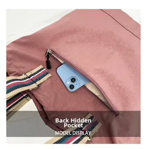 Detail of hidden back zipper pocket on pink nylon tote with striped woven strap