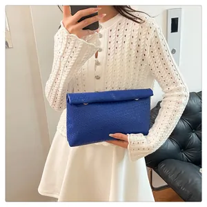 Mirror selfie showing a woman holding a royal blue woven texture PU leather clutch bag