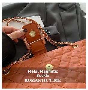 Detail of magnetic gold buckle and quilted leather chain strap on a brown tote bag