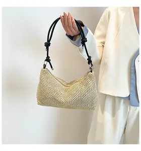 Détail d'un cabas en paille tissé avec bandoulière noire nouée et fermeture éclair
