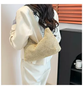 Détail du sac bandoulière en paille tissée avec bandoulière en cuir noir, nœud et boucle