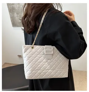 Detail of white quilted tote bag with golden chain strap and leather square buckle