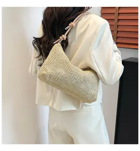 Détail du sac cabas en paille tressée avec bandoulière en cuir rose et nœud décoratif