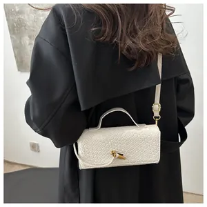 Close-up of a white woven baguette bag with a gold lock on a black coat back view