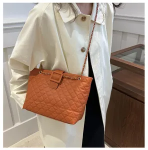 Caramel quilted crossbody bag with chain strap styled with a minimalist beige trench coat