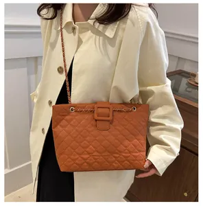 Detail of orange quilted shoulder bag with chain strap and square buckle on model