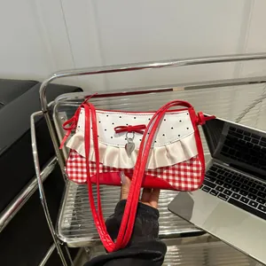 Süße rot-weiß karierte Schultertasche mit Schleife und Herzanhänger in der Hand