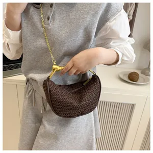 Detail of dark brown woven half-moon bag featuring a unique golden bird-shaped handle
