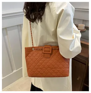Detail of orange quilted tote bag with a large buckle and metal chain strap