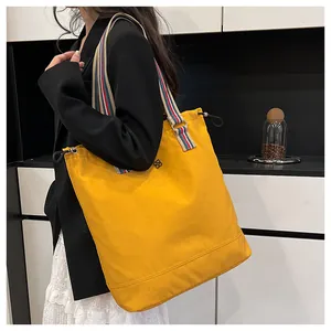 Detail of yellow canvas tote bag with colorful striped strap and drawstring closure