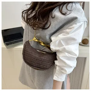 Detailed view of dark brown woven crescent bag with gold twisted handle and chain strap