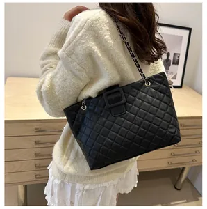 Close-up of black quilted shoulder bag with diamond pattern and metal chain strap