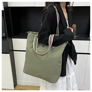 Close-up of army green canvas tote with colorful striped shoulder strap and logo