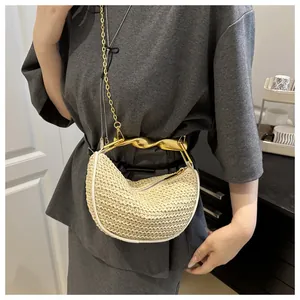 Detail of hand-woven crossbody bag with artistic twisted gold metal handle and chain strap