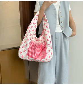 Detail of the reversible floral canvas tote bag featuring a red checkered pocket and bow