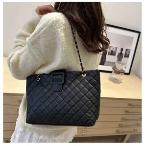 Detail of black quilted tote bag with chain strap and square buckle on shoulder